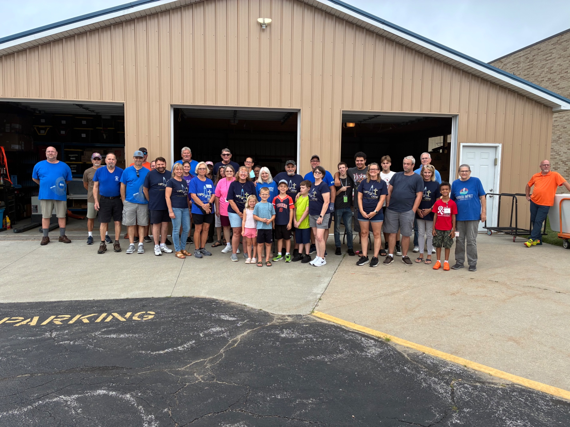 Group photo of about thirty volunteers in front of the warehouse before a pop-up pantry.